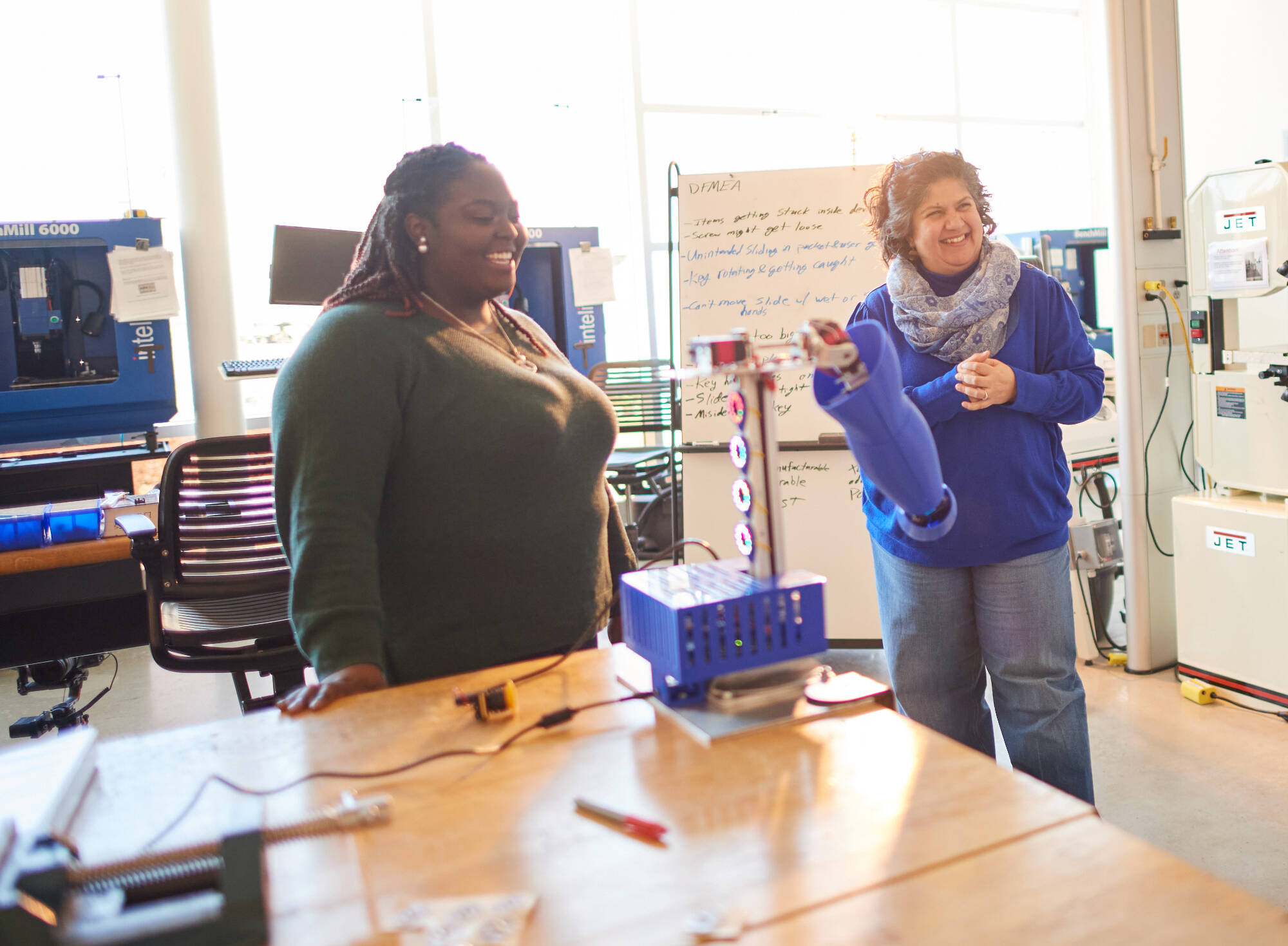 Professor Samhita Rhodes guiding students in a robot arm demonstration